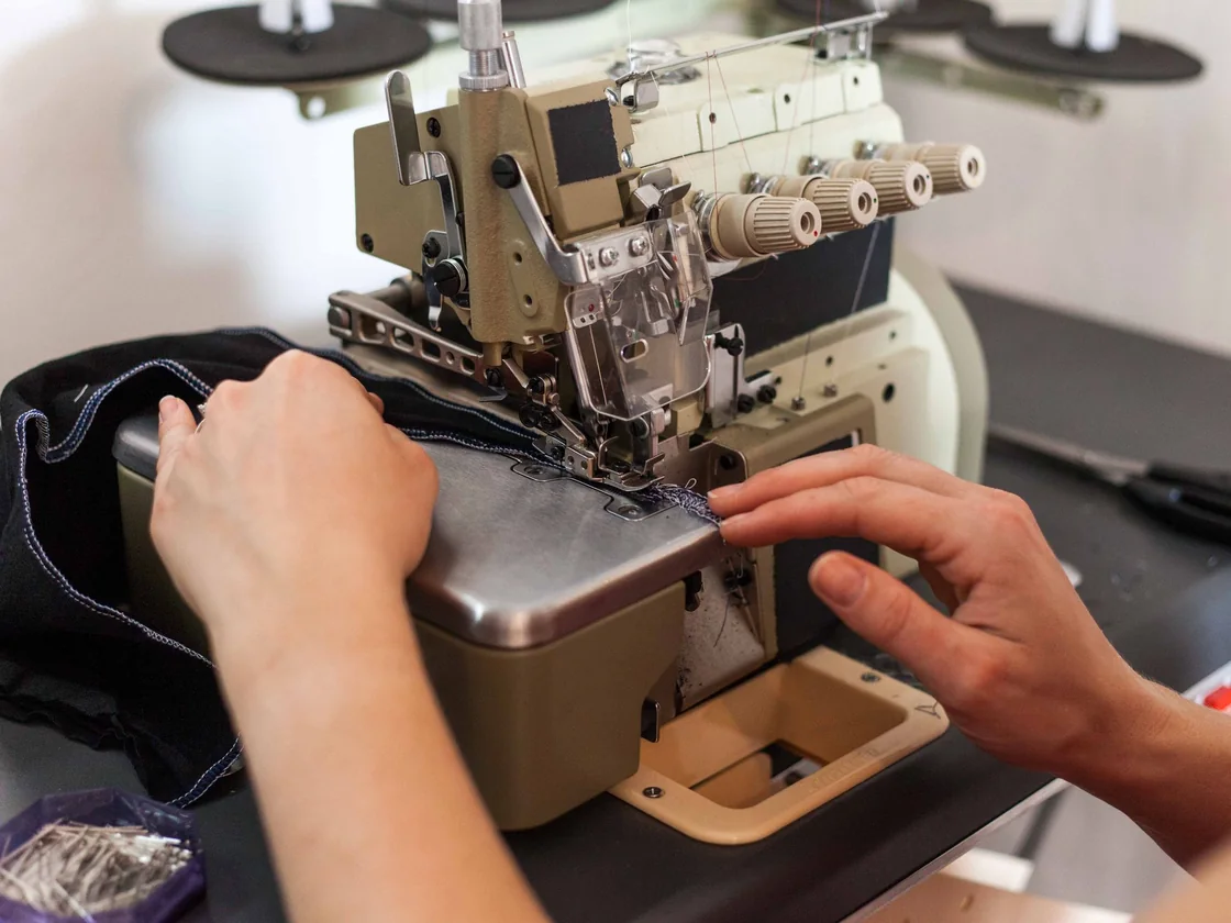 Operator feeding a garment through a 4-thread overlock sewing machine