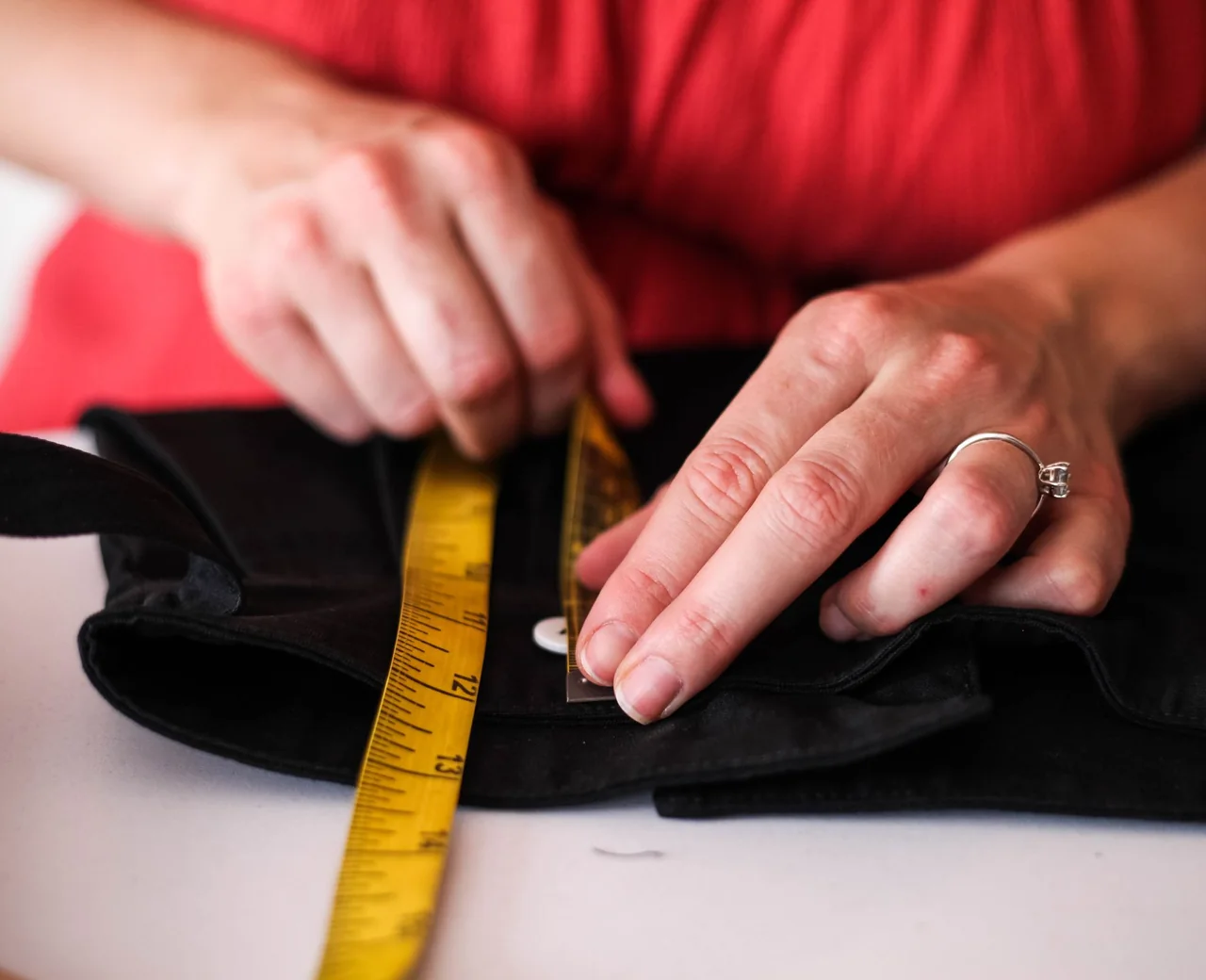 Measuring a finished garment with a tape measure during quality control