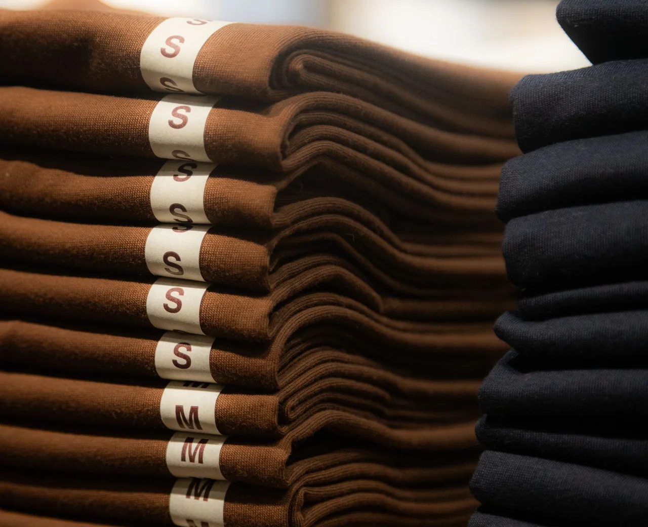 Folded shirts stacked by size from a 30 piece per style streetwear production run