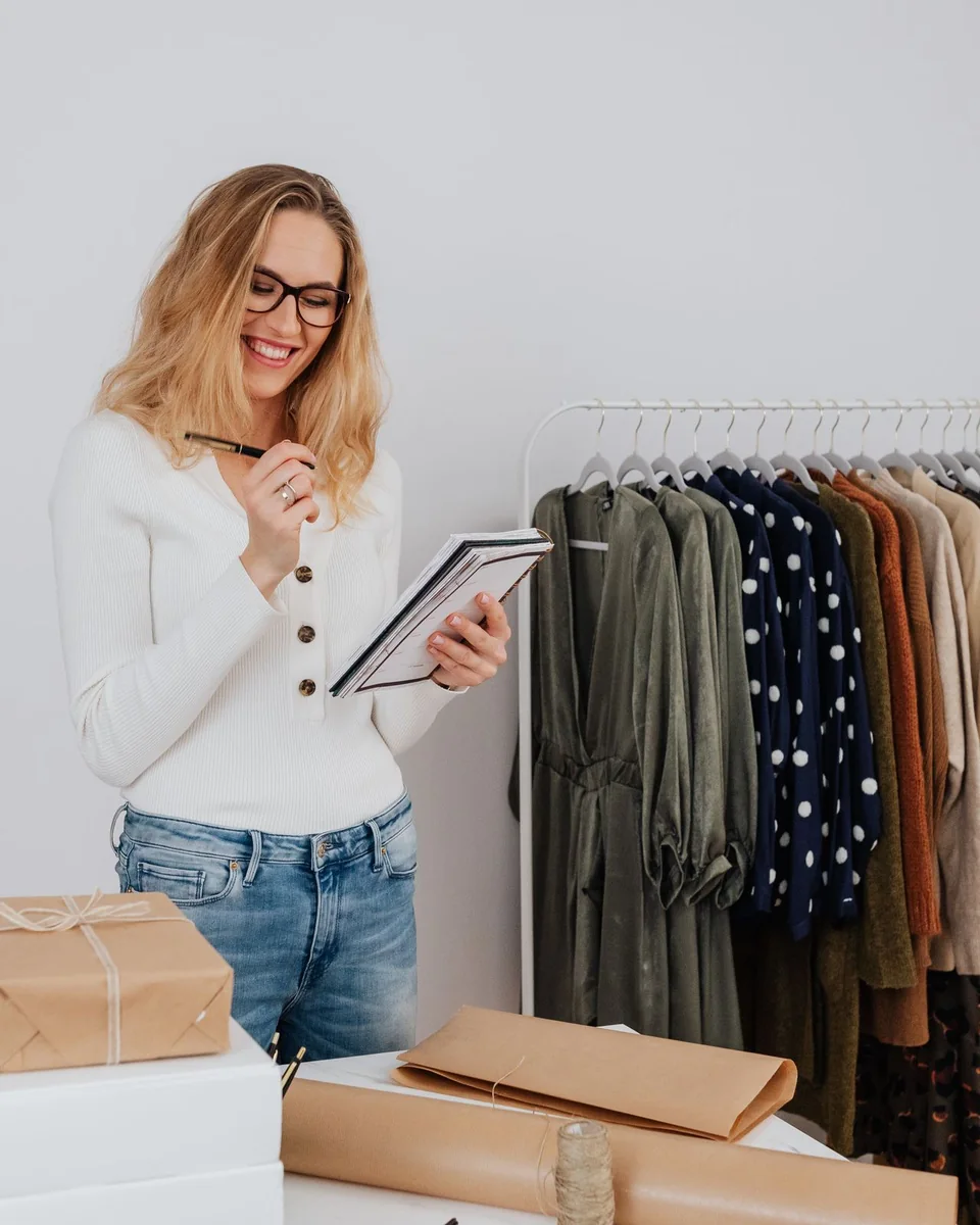 Procurement buyer checking garment stock and production notes in a showroom
