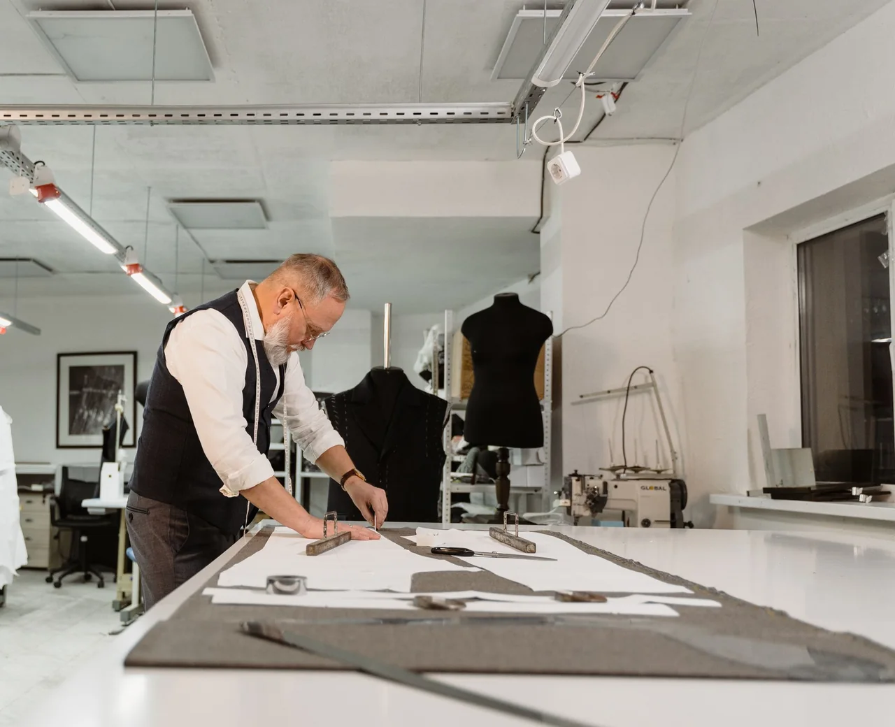Pattern maker marking graded garment patterns on fabric at a cutting table