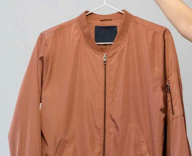 Rust-coloured MA-1 style bomber jacket with rib knit collar, front zipper and sleeve zip pocket from a bomber jacket manufacturer