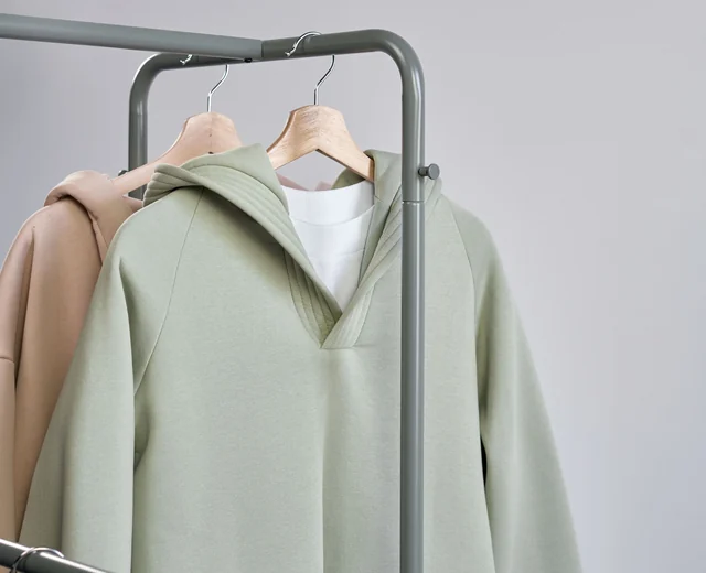 Sage hoodie and white tee hanging on a rail after a cut and sew production run