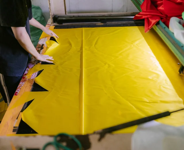 Worker spreading fabric on a long cutting table before panels are cut