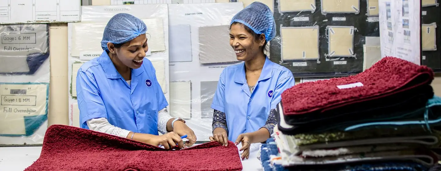 Two quality inspectors checking fabric pieces on an inspection table