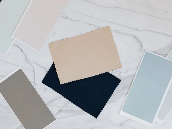 Fabric swatches and color cards laid out on a marble table for a new apparel order