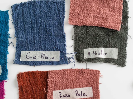 Textured fabric swatches with handwritten color names laid out on a white table