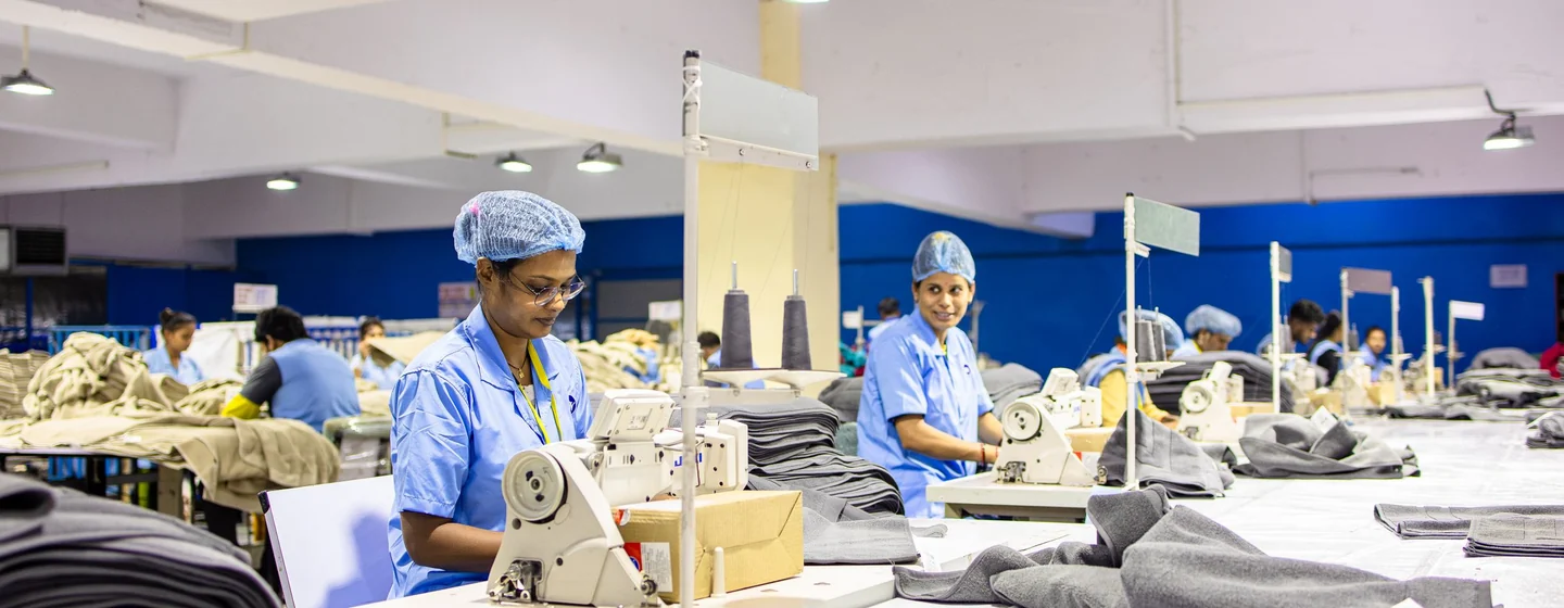 Sewing operators at rows of machines on a busy garment factory floor