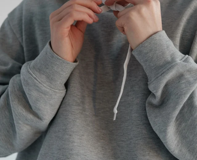 Grey pullover hoodie with a white drawcord, made to spec by a hoodie supplier