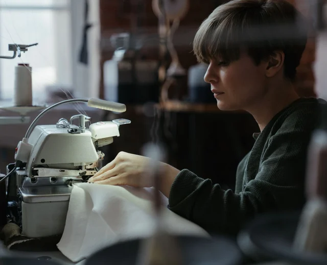 Machinist feeding fabric through an overlock machine on a sewing line