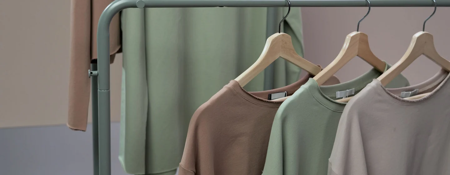 Sweatshirts in brown, sage and stone hanging on a metal clothing rail