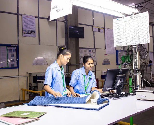 Two quality control inspectors checking finished textiles at a factory inspection station