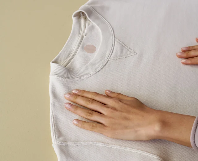 Hand smoothing a cream crewneck sweatshirt made by a small batch clothing manufacturer